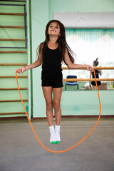 Girl gymnast jumping on skipping-rope in gym