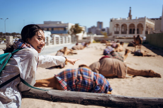 Young tourist happy to see camels in Eastern bazaar in Qatar in