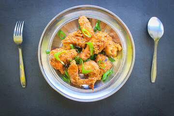 crispy spicy chicken wings sesame, and leek, on black background
