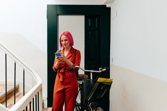 Woman with bicycle texting on phone on staircase