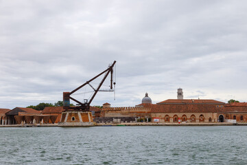 Industrial shipyards (Arsenale di Venezia) in Italy, Venice. Loading cranes and docks. Cloudy,...