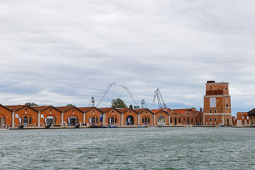 Industrial shipyards (Arsenale di Venezia) in Italy, Venice. Loading cranes and docks. Cloudy,...