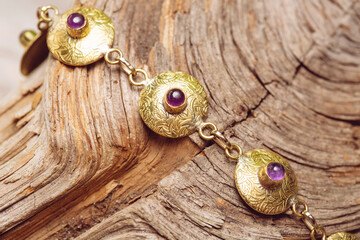 golden discs mineral stone brass bracelet with amethyst on wooden background