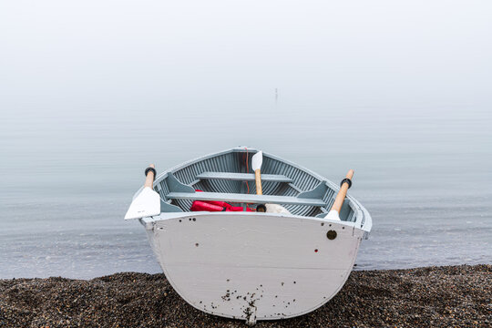 Traditional wooden rowboat sitting on a beach in fog with traditional wooden oars.  Shot in the Toronto Beaches in June.