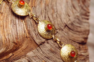 golden discs mineral stone brass bracelet with carneol on wooden background