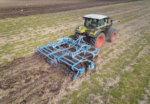 Luftaufnahme eines Schleppers mit einem Grubber bei der Arbeit auf dem Acker.Landwirtschaftliches Symbolfoto.