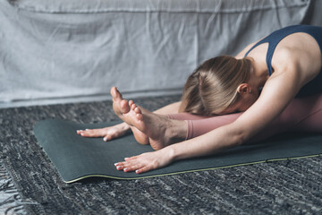 Sporty and healthy woman making seated forward bend pose