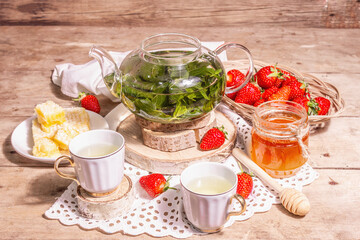 Teatime concept with aromatic mint tea, ripe strawberries, sweet honey