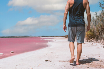 Man walking along beach near pink sea