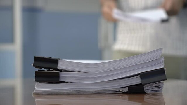 Man walks into the room and puts the papers on the table.