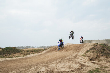 Obraz premium Motorcyclist jumping and riding on rear wheel at enduro motocross training ground