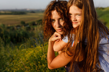 young red-haired mom and her wonderful red-haired daughter have fun outdoors dressed in dresses