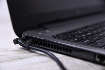 Laptop, computer is charging from a 220-volt outlet on a desk near the wall. Energy, accumulation. Mockup