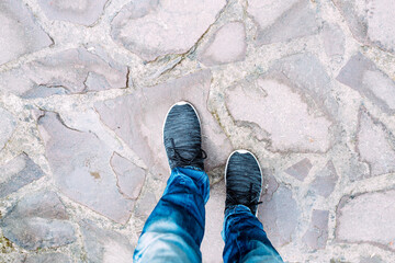 Faceless person standing on stone ground in daytime