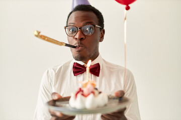 Portrait of cute funny young dark skinned man wearing elegant clothing blowing whistle holding...