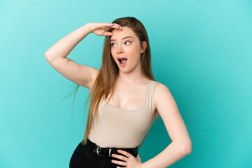 Teenager girl over isolated blue background doing surprise gesture while looking to the side