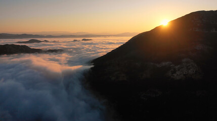 Aerial view of mesmerizing landscape of mountains of setting sun and white clouds on a warm summer evening. Concept of pristine nature and relaxation in ecologically clean corners of the planet