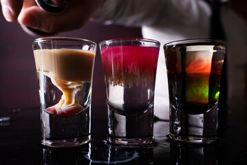 Barman preparing cocktail shots at the bar counter. Barman mixing drinks at the night club