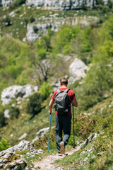 Naklejka na ściany i meble Traveler with backpack trekking on cliff
