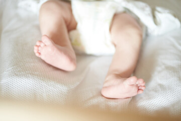 Fototapeta na wymiar Baby legs on white sheet, newborn baby 1 month, care and love with copy space. High quality photo