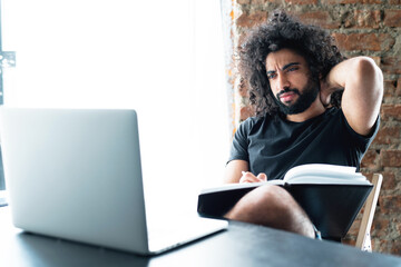 the man is holding his neck because of the motionless work in the office at the laptop. massage and health concept