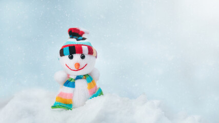 Merry christmas and happy new year greeting card with copy space. Happy Toy of snowman in cap and scarf standing in winter snow background. Christmas fairytale.