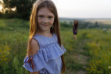 young red-haired mom and her red-haired daughter launch a throwing saucer outdoors during sunset