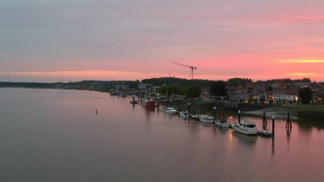 Small pier with many docked boats and majestic colorful sunset, aerial view