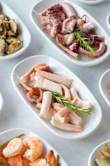 Set of Seafood Dishes. Seafood on a plate. On a white wooden background. Selective focus octopus salad. Lakerda, octopus salad, shrimp, fish salad
