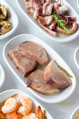 Set of Seafood Dishes. Seafood on a plate. On a white wooden background. Shrimp, lakerda, octopus salad, mussels with marinade, fish salad