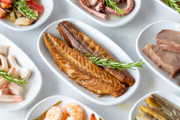Set of Seafood Dishes. Seafood on a plate. On a white wooden background. Selective focus mackerel fillet. Shrimp, lakerda, octopus salad, mackerel, fish salad