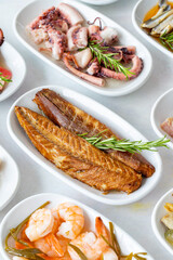Set of Seafood Dishes. Seafood on a plate. On a white wooden background. Selective focus mackerel fillet. Shrimp, lakerda, octopus salad, mackerel, fish salad