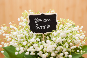 You are loved - beautiful christian card, text on blackboard with white flowers, religion and...
