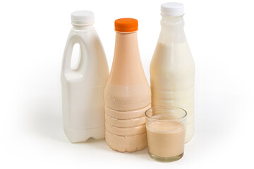 Glass of fermented milk against dairy products bottles, side view