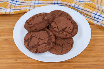 Round chocolate cookies on dish on a wooden surface