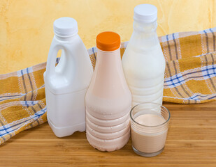 Glass of fermented milk against plastic bottles of dairy products