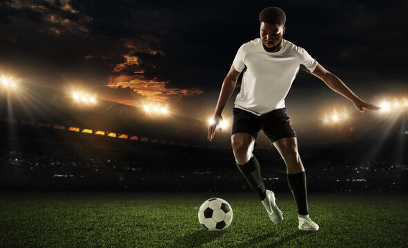 One African man, male football or soccer player training at stadium - motion, action, activity concept