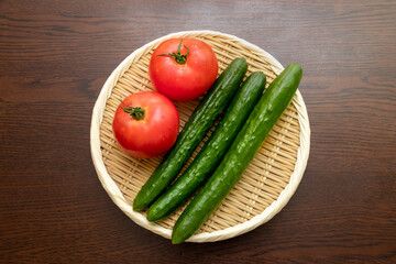 丸い竹ザルにのせられたトマトとキュウリ