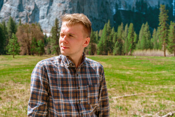 Naklejka na ściany i meble A young man with a shirt enjoys mountain views in Yosemite National Park on a summer day