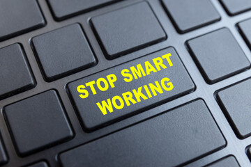 Black notebook keyboard, with key with text "stop smart working" in yellow. Holidays. Back to the office.
