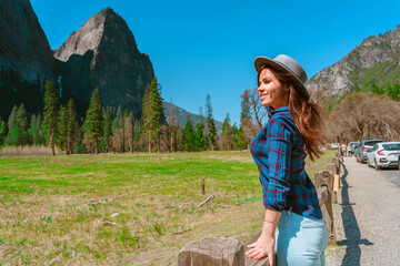 Naklejka premium A young female tourist in a hat enjoys mountain views in Yosemite National Park