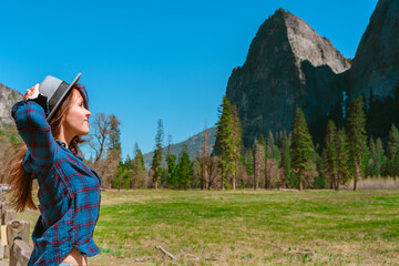 Fototapeta na wymiar A young female tourist in a hat enjoys mountain views in Yosemite National Park