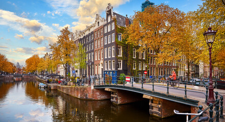 Netherlands Amsterdam. View at river Amstel with traditional houses at bank and boats at water...