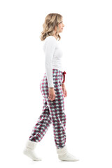 Young pretty woman in pajamas and winter socks walking and looking ahead. Side view. Full body...