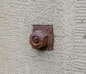 large rusty red metal nut on an old 19th century wall