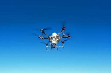Agricultural drone in flight on a background of blue sky. Field spraying new technologies