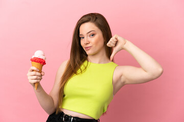 Teenager girl with a cornet ice cream over isolated pink background proud and self-satisfied