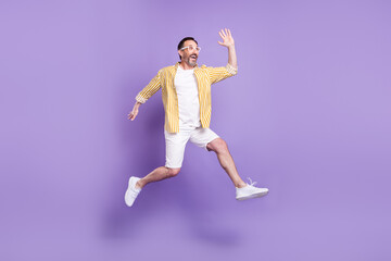 Fototapeta na wymiar Photo of impressed friendly mature man dressed shirt glasses jumping waving arm empty space isolated purple color background