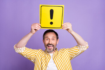 Photo of cute impressed age gentleman wear striped shirt holding exclamation point card smiling isolated violet color background