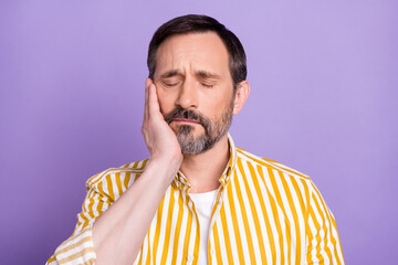 Photo of unhappy upset mature man dressed yellow shirt arm cheek having toothache isolated purple...